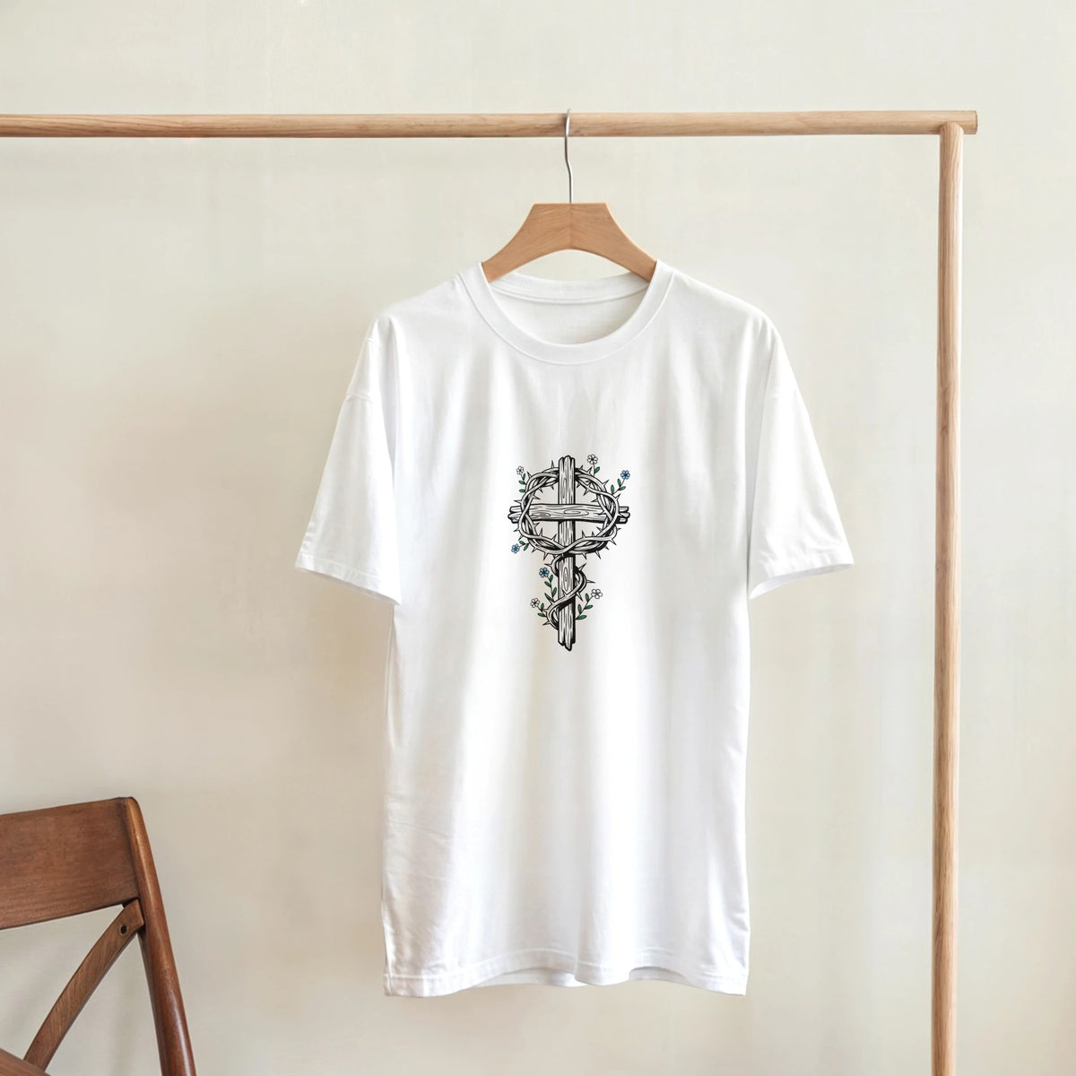 White Crown Of Thorns Cross Adult Tee, hanging on a wooden rack, room mockup